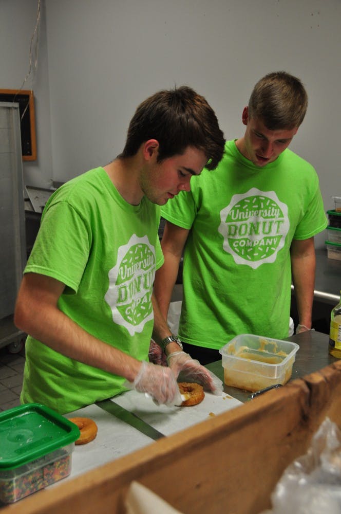 Tommy Jernigan (left) shows&nbsp;David Mote (right) how to ice a doughnut at the University Donut Company on East Magnolia Avenue on Sept. 26, 2016. The shop opened nearly two weeks ago and has a food truck on campus.