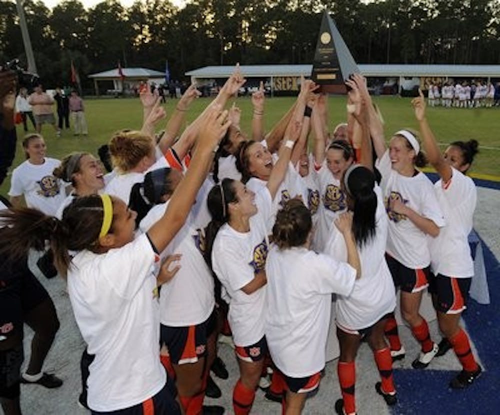 The women of the Auburn soccer team celebrate and hoist the championship trophy after winning their first-ever SEC Tournament after a 3-2 victory over Florida. (Todd Van Emst)