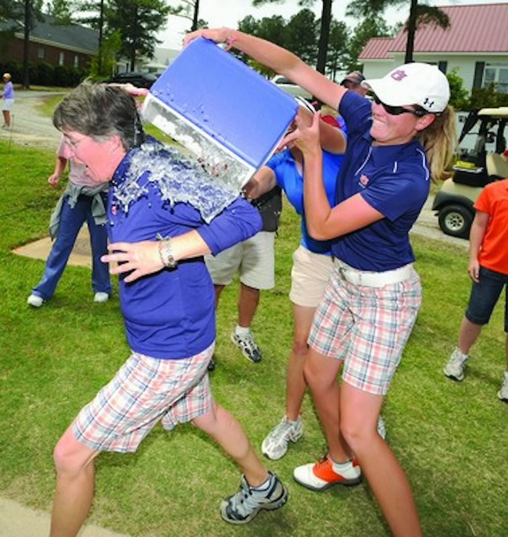 Auburn golfers Cydney Clanton, front, and Madison Overbey dump a cooler of ice water on coach Kim Evans after Auburn won the SEC Championship Sunday.SEC Women's Golf Championships on Sunday, April 19, 2009 in Columbia, SCTodd Van Emst