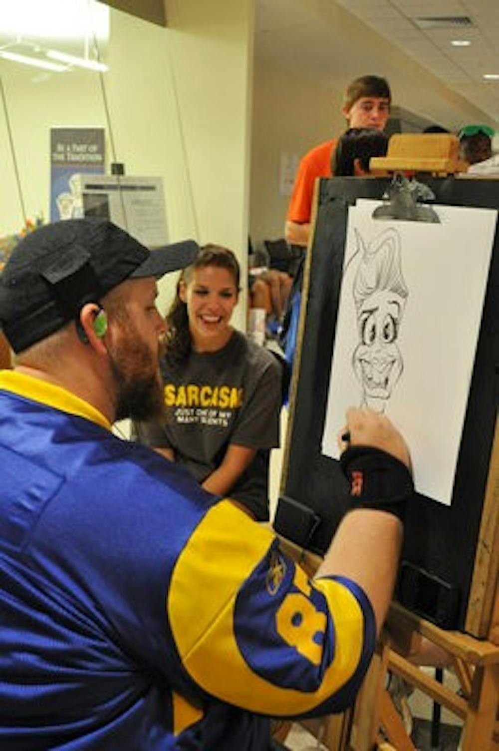 Cartoonist Jeremy Townsend draws a caracature of Kelly Tsaltas, freshman in journalism, at the Block Party in the Student Union on Friday. (Christen Harned/ASSISTANT PHOTO EDITOR)