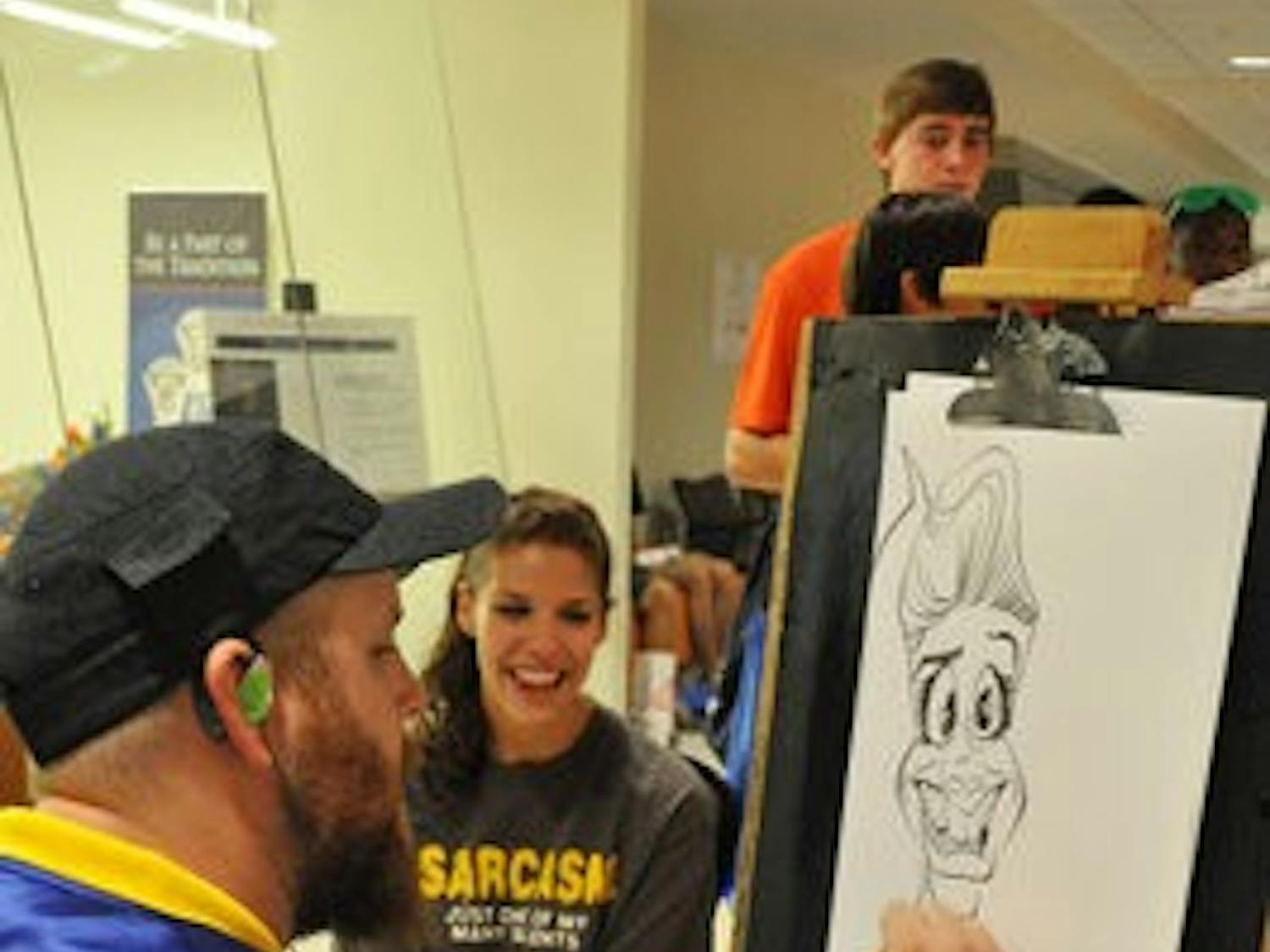 Cartoonist Jeremy Townsend draws a caracature of Kelly Tsaltas, freshman in journalism, at the Block Party in the Student Union on Friday. (Christen Harned/ASSISTANT PHOTO EDITOR)