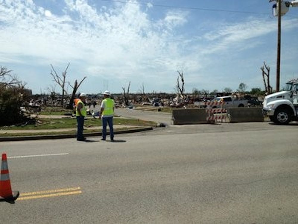 Workers help clean up and block off heavily damaged areas in east Moore, Okla.