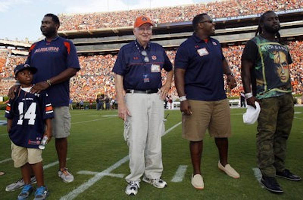 Buddy Davidson, center, is surrounded on the field at Jordan-Hare Stadium by former players (from left) Antwoin Daniels, his son Buddy, Wayne Dickens and Tez Doolittle. (Todd Van Emst / Opelika-Auburn News)