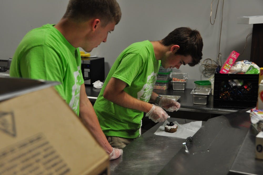 Tommy Jernigan tops a doughnut with blueberries as David Mote watches&nbsp;at the University Donut Company in Auburn, Ala., on Sept. 26, 2016.&nbsp;