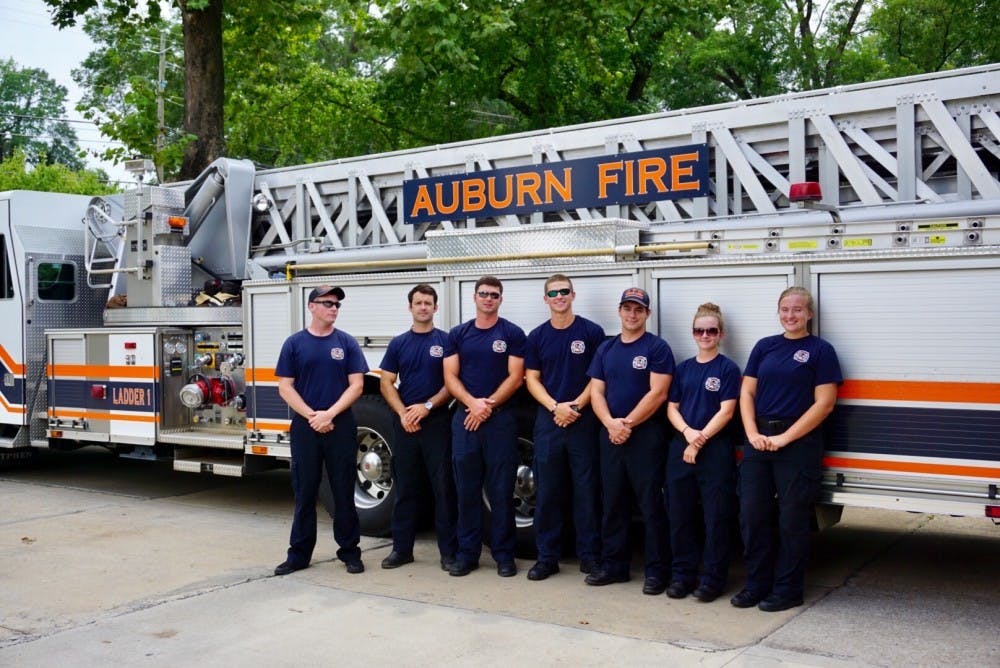 <p>Two certified student interns stand alongside fellow city of Auburn firefighters in front of the department's ladder truck on Tuesday, July 11, 2017 in Auburn, Ala.</p>