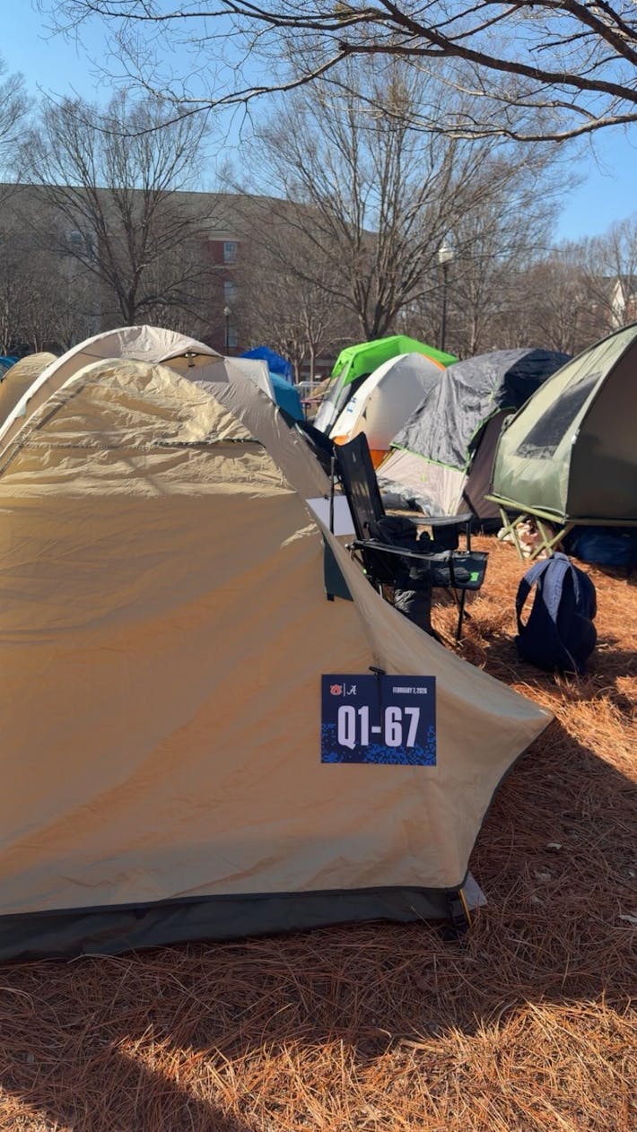 A yellow tent is set up in a grassy area, displaying a blue sign with the text "Q1-67" attached to it.