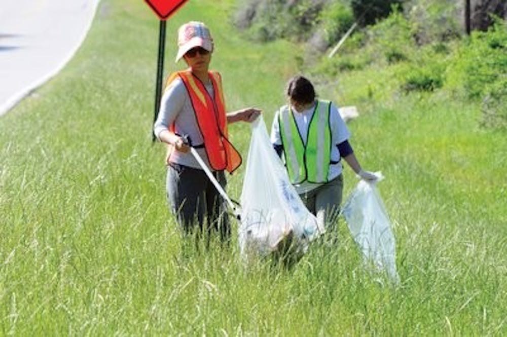 Bochaor Hu, graduate student in fisheries, and Savannah Warren, senior in fisheries, help pick up trash along the road Saturday. (Christen Harned / ASSISTANT PHOTO EDITOR)