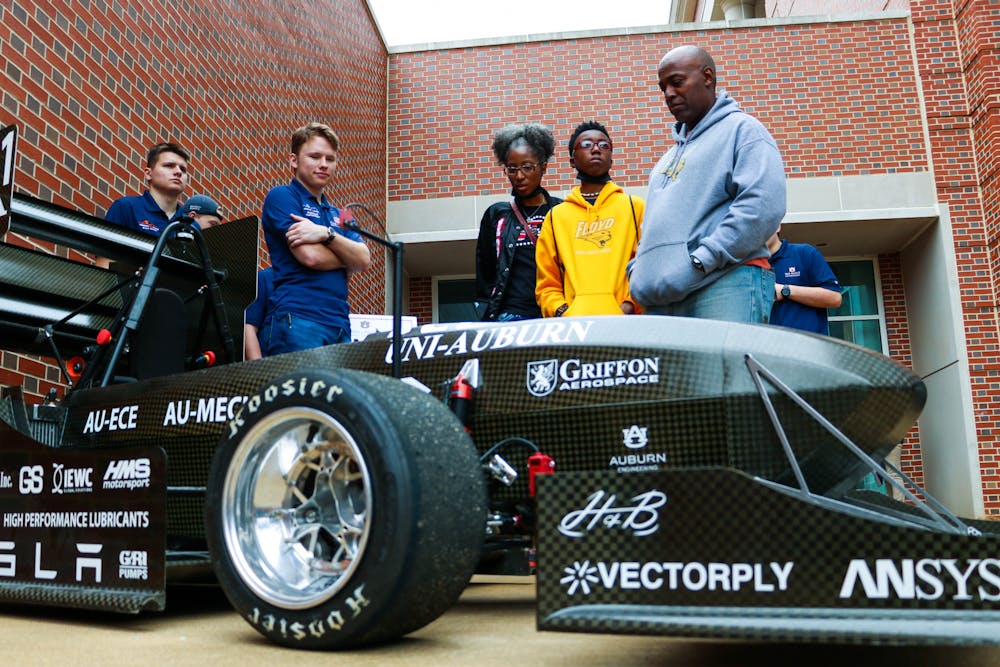 Brothers Brent (left) and Braden Newell speak with Johnnetta Baskin-White, Brayden White and Bobby White during the Samuel Ginn College of Engineering's E-Day event on Feb. 24, 2023. The racecar War Eagle Motorsports built is electric and made almost entirely of carbon fiber materials according to Braden.