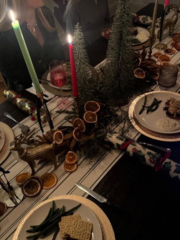 A table is set for a Christmas party with candles, orange slices and a meal.