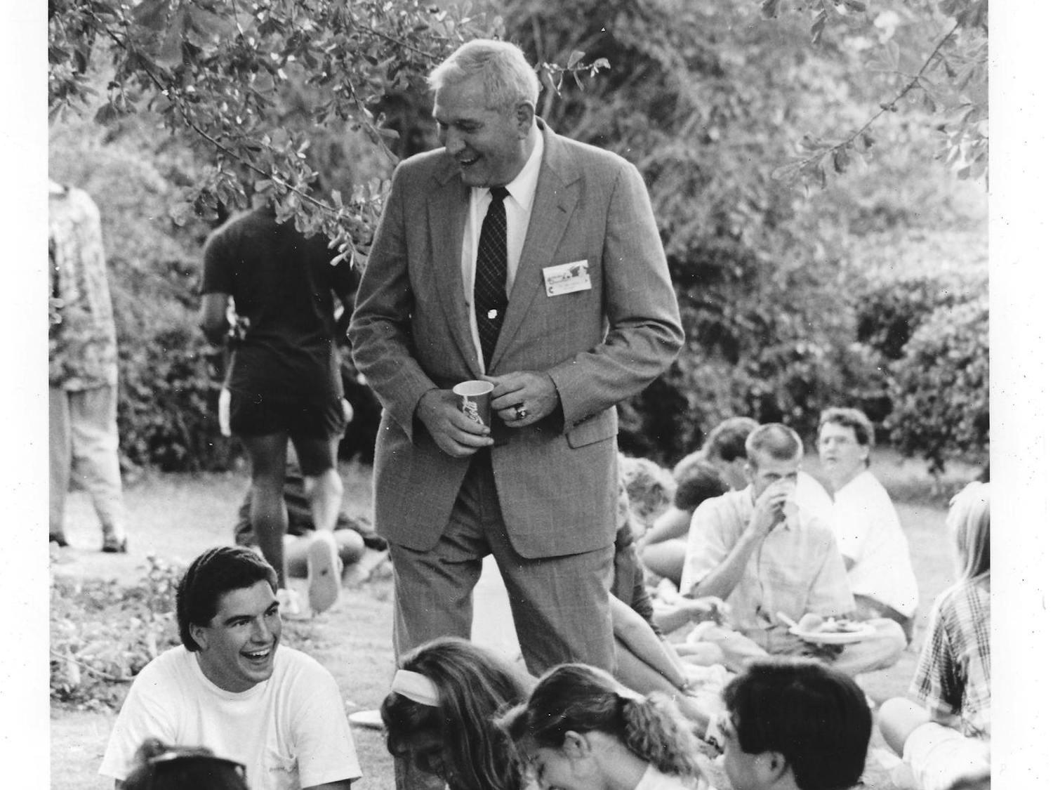 A group of students socializing with each other and a man in a suit. Archive photo.