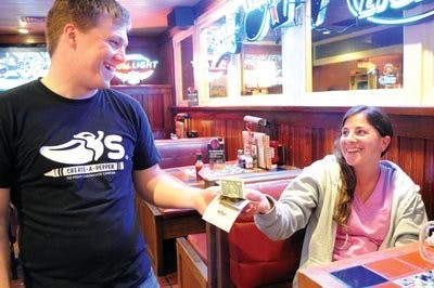 Kaylee Wilson pays her bill with cash to Chili's bartender Joshua Jones. Chili's general manager Eric Wilson said the number of customers paying with TigerCards has decreased dramatically since the meal plan was created in 2008. (Christen Harned / Assistant Photo Editor)