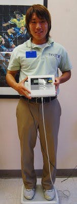 Clinical intern Yuki Kariya demonstrates the weigh-in process at HealthPlus Fitness Center in Opelika. (Jordan Dale / Photo Staff)