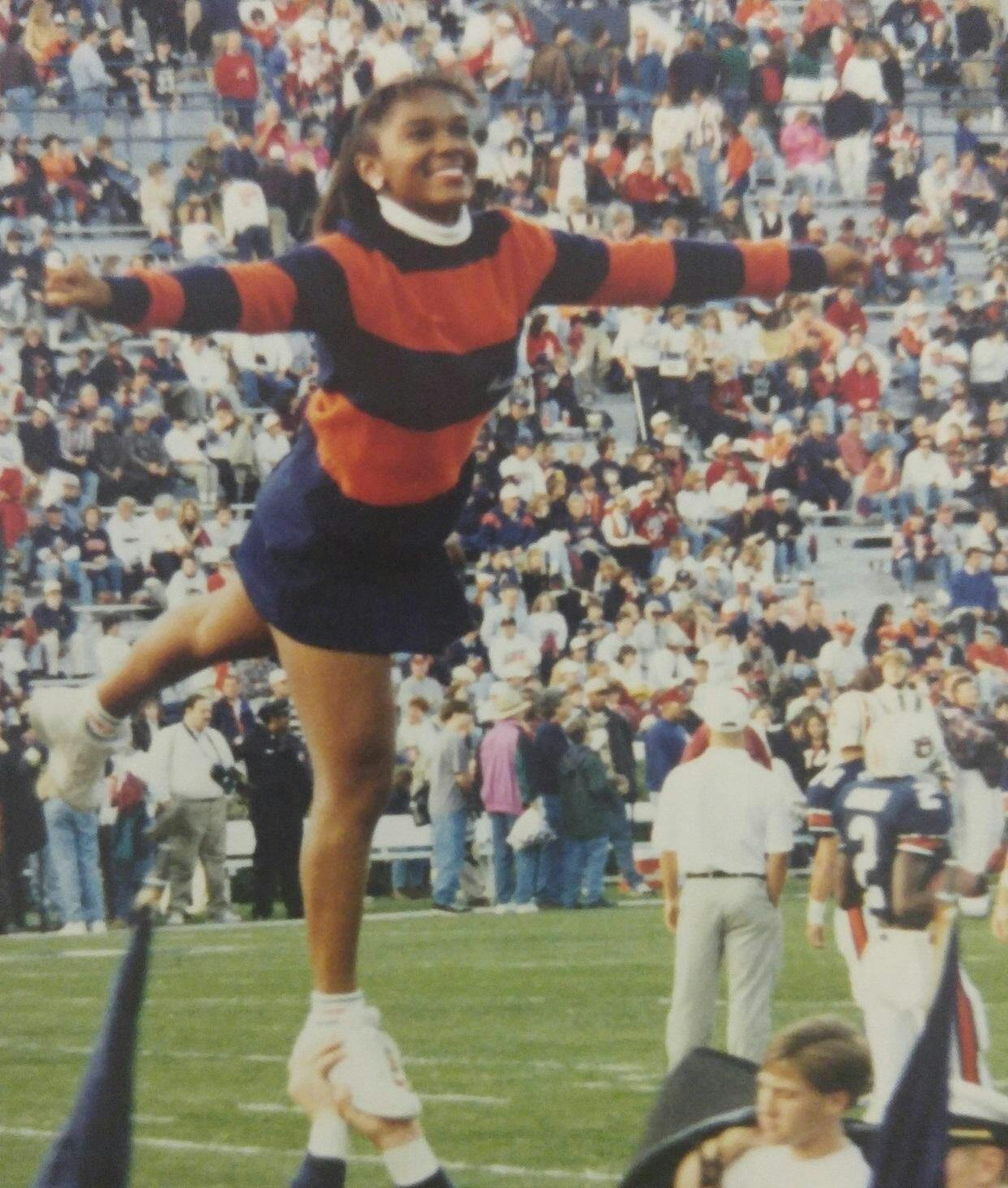 Wearing an orange and blue sweater, Danyelle Hillman is lifted and poses for a stunt. Contributed by Danyelle Hillman.