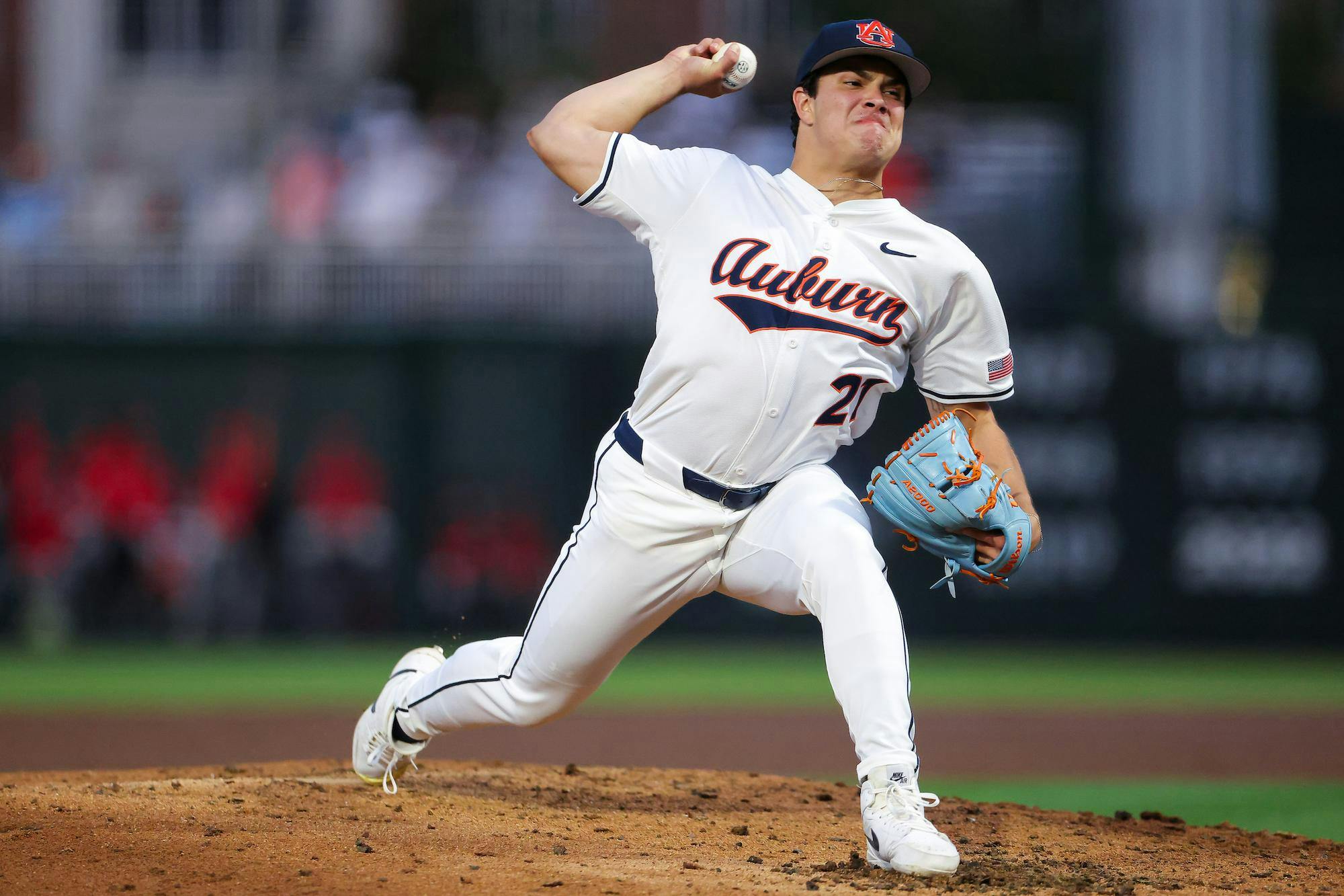 A baseball pitcher, wearing a white uniform with "Auburn" on it, is winding up to throw a baseball.