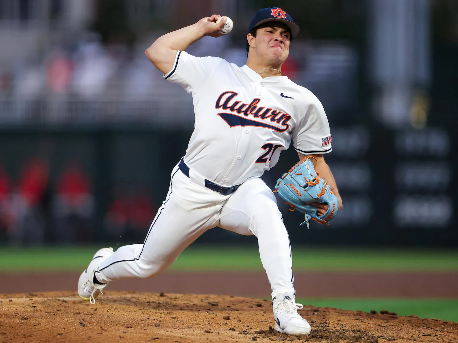 A baseball pitcher, wearing a white uniform with "Auburn" on it, is winding up to throw a baseball.