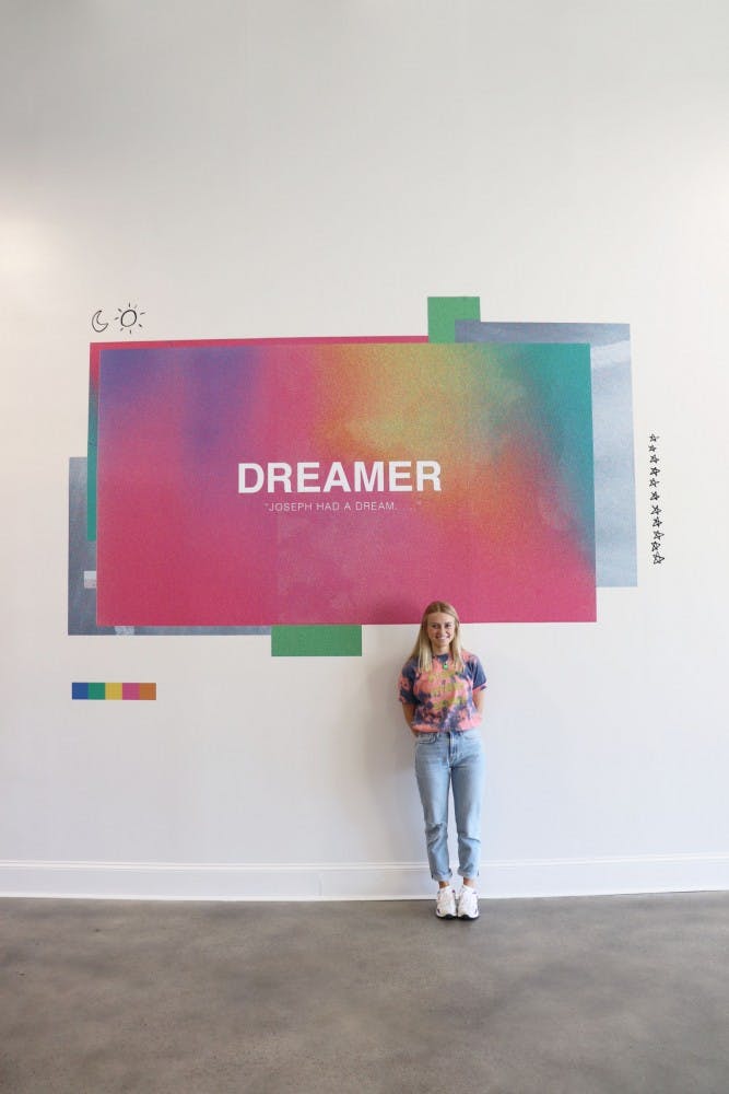 Graphic designer Megan Kesting featured standing by her artwork