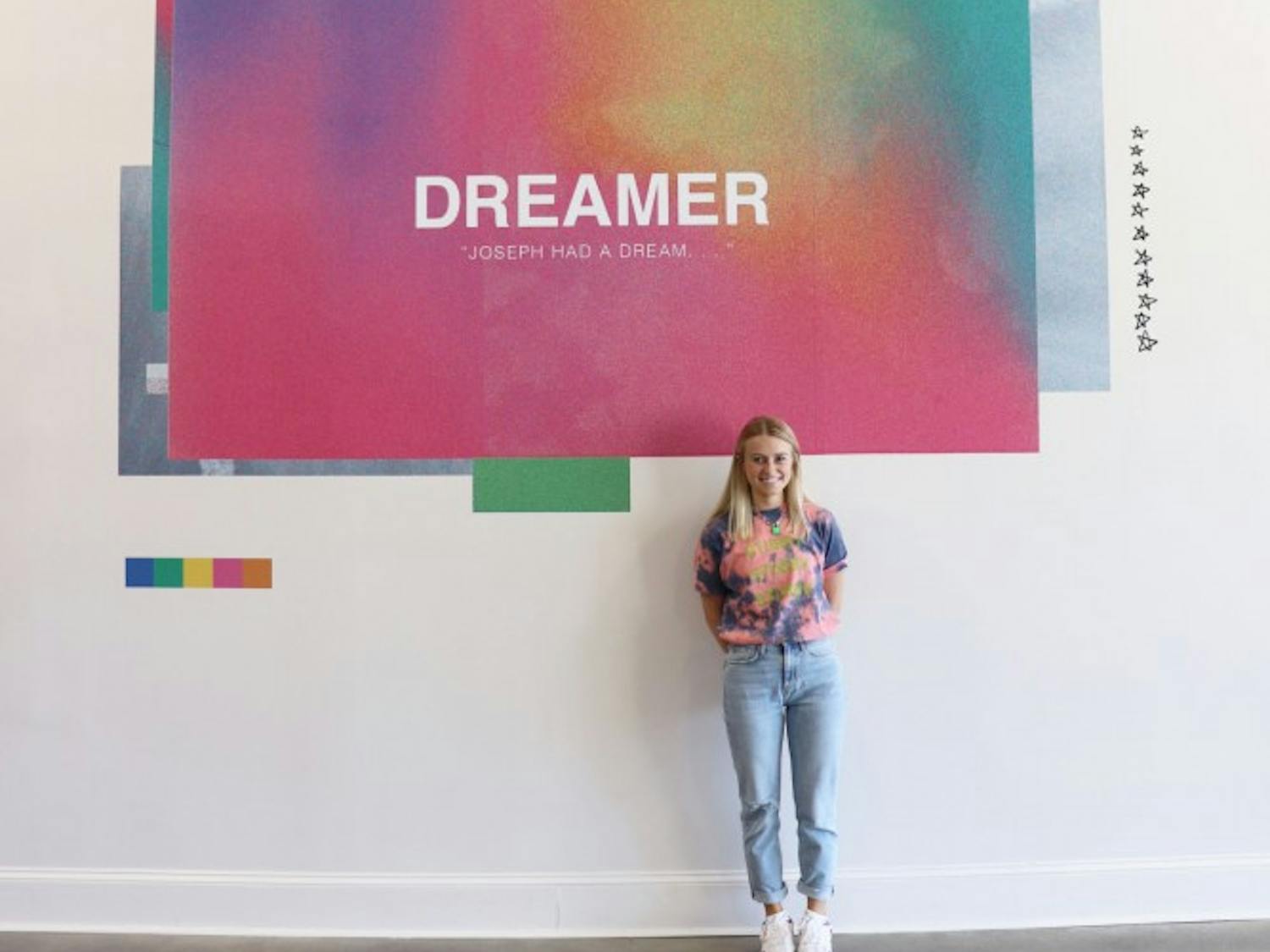 Graphic designer Megan Kesting featured standing by her artwork