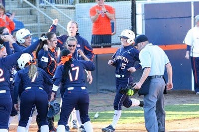 Senior shortstop Lauren Guzman, No. 5, is greeted with cheers as she runs home after hitting a grand slam against Oklahoma State University Friday. (Rebecca Croomes / PHOTO EDITOR)