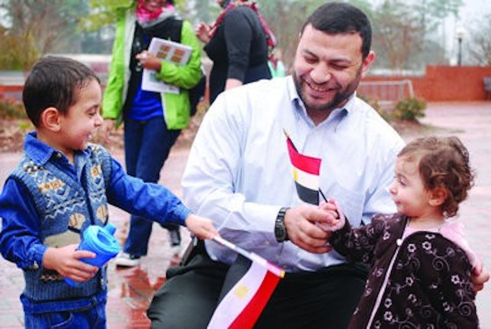Mohamed Eldessouki, Ph.D. student in polymer and fiber engineering, plays with his children, Omar, 3, and Nada, 2, at the demonstration Feb. 1. Omar and Nada wave Egyptian flags. (Jillian Clair / News Editor)