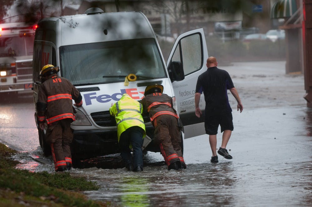 Auburn firefighters push a stranded Fed-Ex van behind Flints Crossing shopping center during a flash flood event on Thursday, Dec. 24, 2015, in Auburn, Ala.