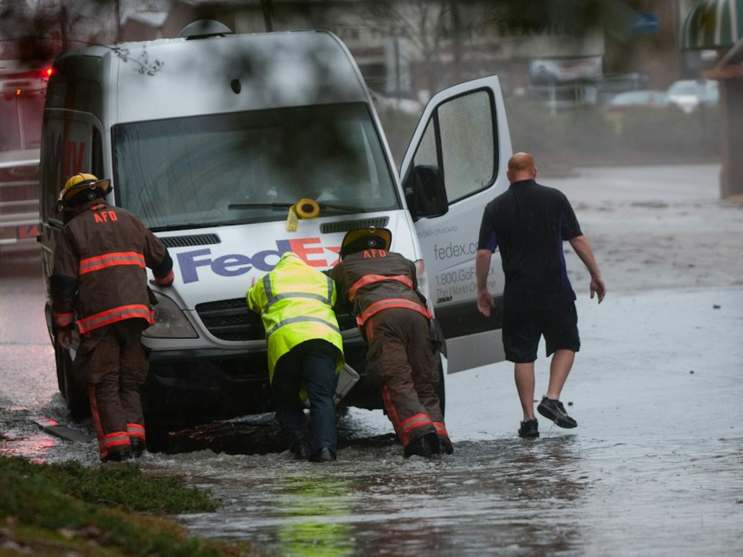 Auburn firefighters push a stranded Fed-Ex van behind Flints Crossing shopping center during a flash flood event on Thursday, Dec. 24, 2015, in Auburn, Ala.