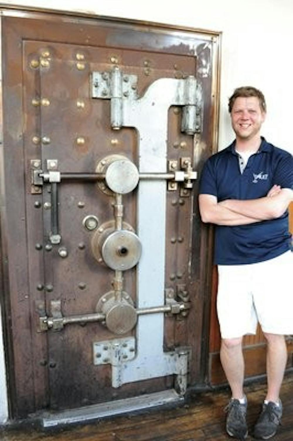 The Bank Vault's assistant manager Will Rankin poses by the bar's famous vault which is now used as a storage room. (Christen Harned / Associate Photo Editor)