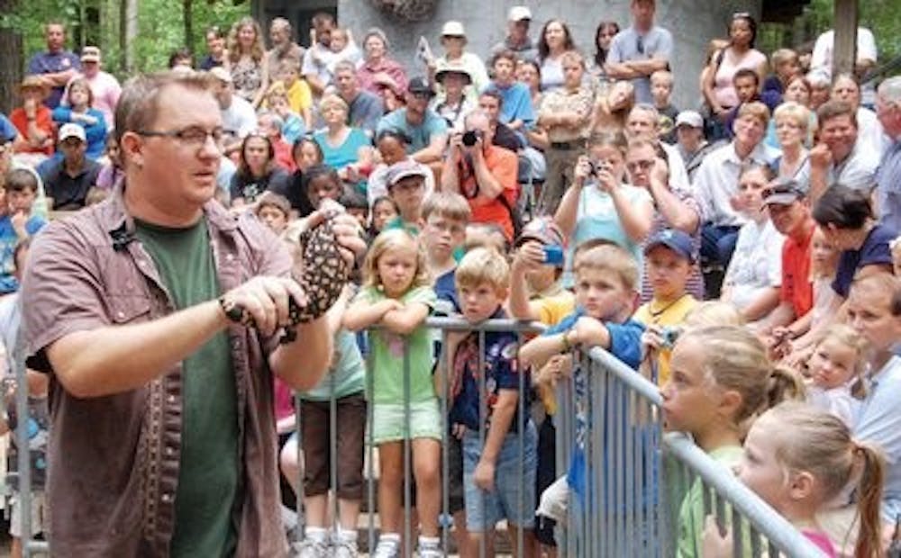 A crowded amphitheater surrounds Mike Wines as he holds a Gila Monster and explains why the lizard is called a "fire-breathing dragon." (Robert Lee / WRITER)
