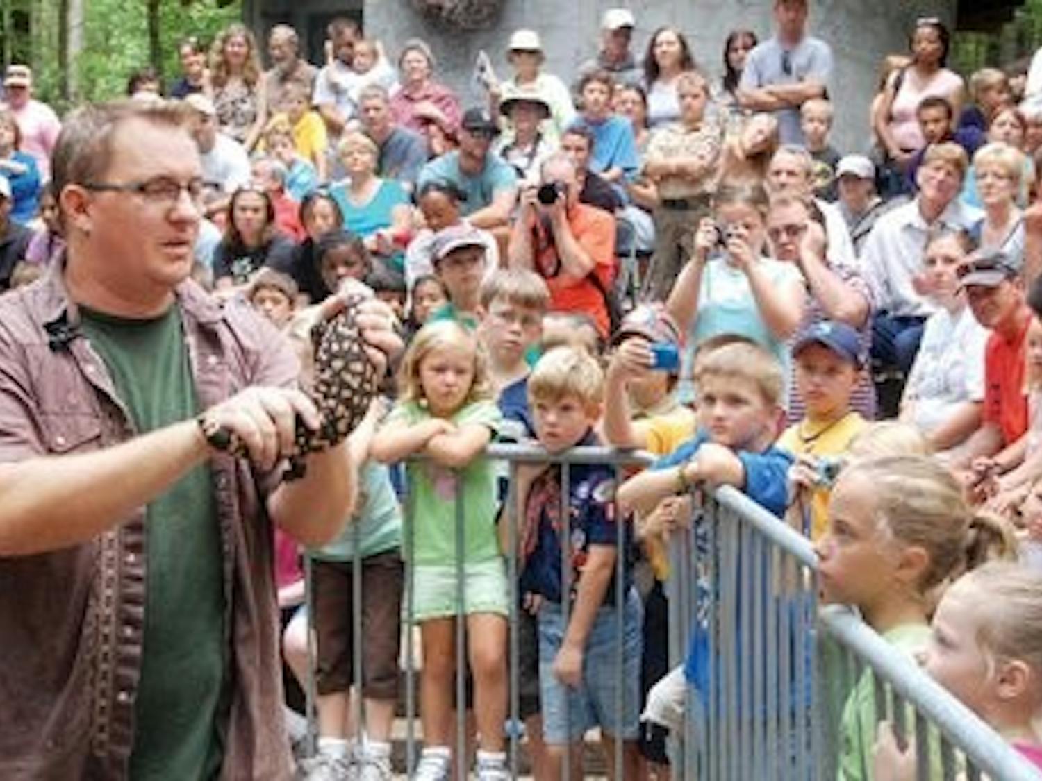 A crowded amphitheater surrounds Mike Wines as he holds a Gila Monster and explains why the lizard is called a "fire-breathing dragon." (Robert Lee / WRITER)