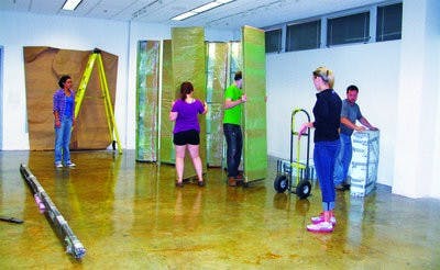 Students help artist Noah Kirby install pieces of his exhibit at Biggin Hall. (CONTRIBUTED)