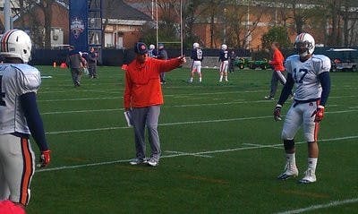 Defensive coordinator Ellis Johnson runs drills with sophomore linebacker Kris Frost Friday morning. (ANDREW YAWN / SPORTS REPORTER)