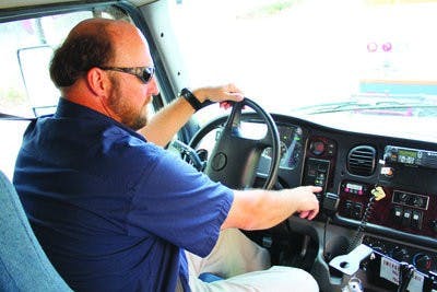 Transit bus driver, Edward Meek, pushes the ignition button in one of the hybrid buses ( Alex Sager / PHOTO EDITOR)