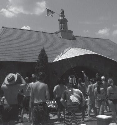 ROTC member Peter Glaeser climbs the Creekside club house to display an American flag on July 4. (Courtesy of Jayne Dees)