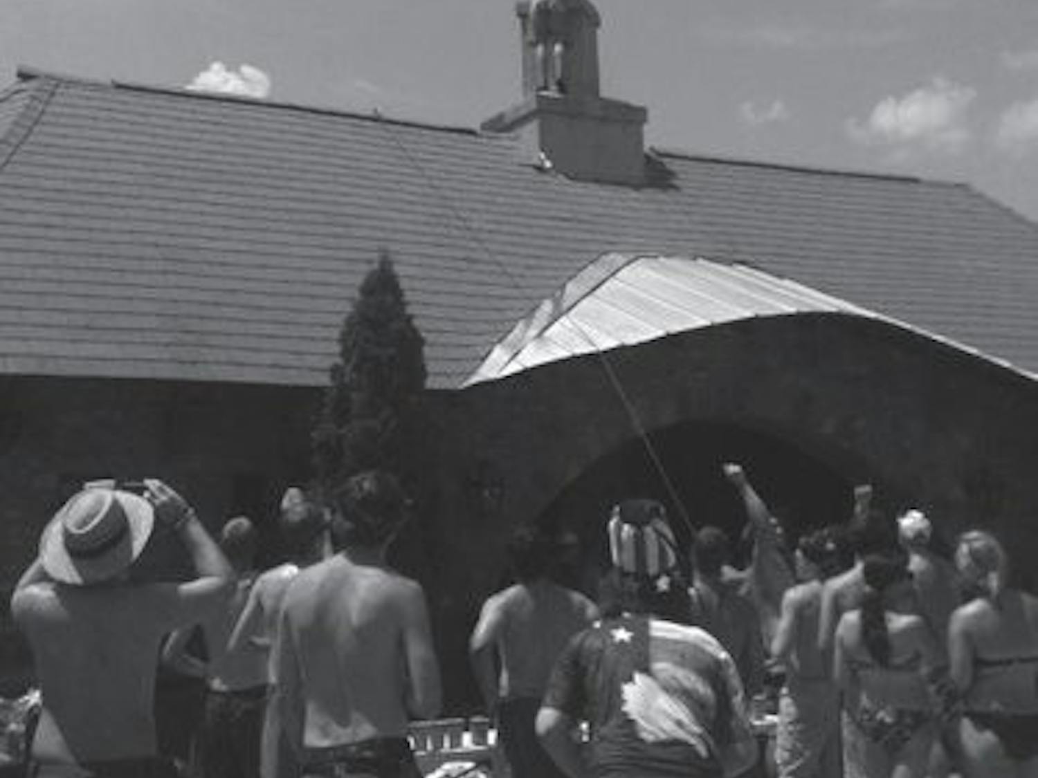 ROTC member Peter Glaeser climbs the Creekside club house to display an American flag on July 4. (Courtesy of Jayne Dees)