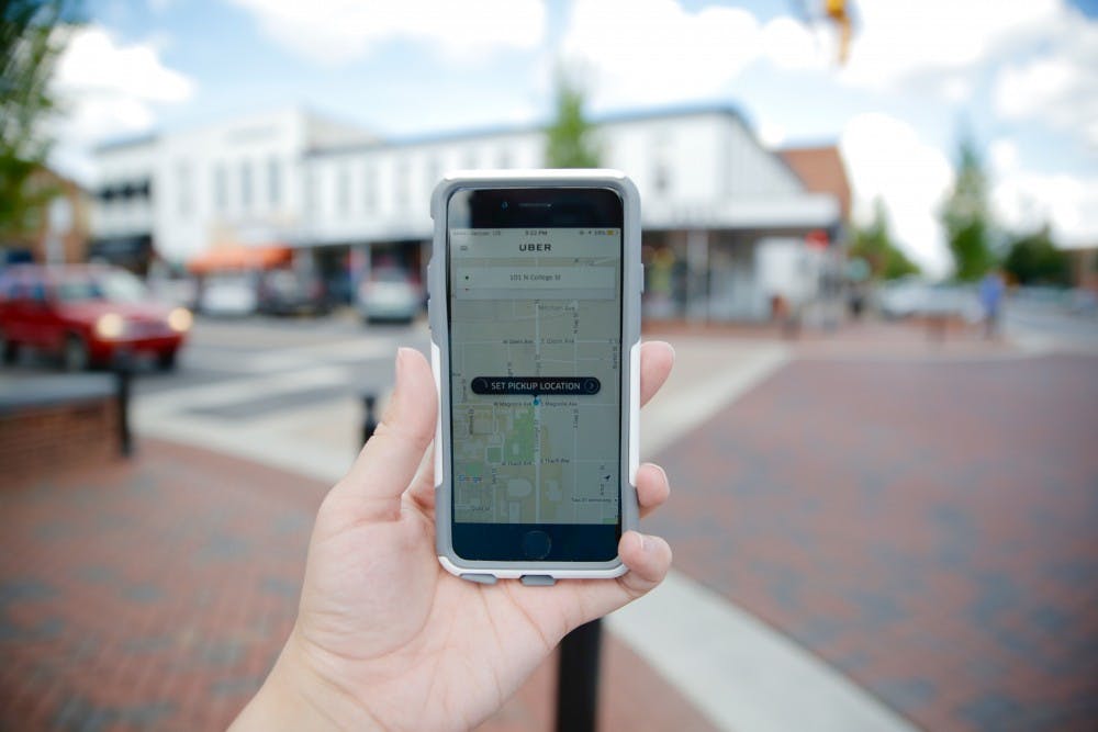 <p>A student looks at their Uber app in downtown Auburn.</p>