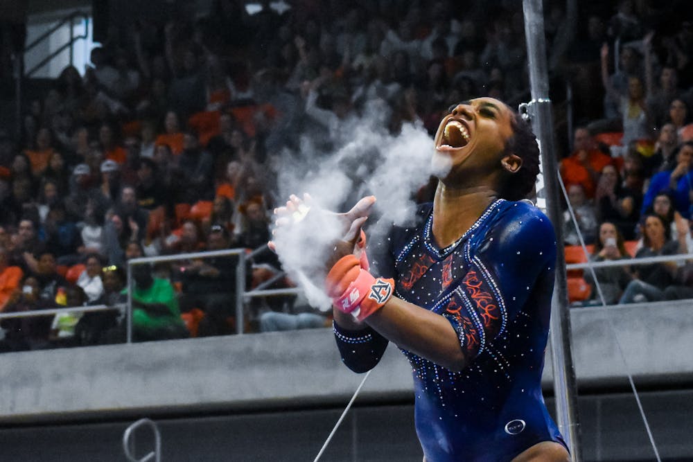 <p>Derrian Gobourne celebrates with chalk-filled hands after competing on bars during the NCAA Women's National Gymnastics Sweet 16 in the Neville Arena in Auburn, Alabama.</p>