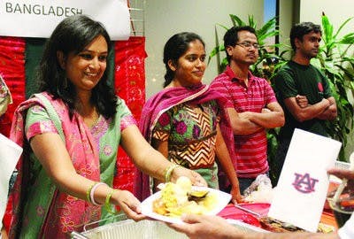 Safina Hussain, graduate student in industrial engineering, serves food at the Bangladesh table. (Emily Adams/PHOTO EDITOR)