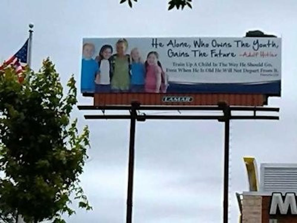 A billboard at the Village Mall in Auburn featured five children, a quote from Adolf Hitler and a bible verse. (Photo by Raye May | Photo & Design Editor)