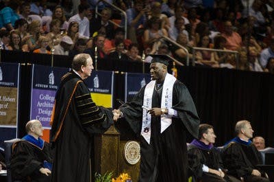 Defensive lineman LaDarius Owens, No.10, is handed his degree by Jay Gogue. \0x200B
