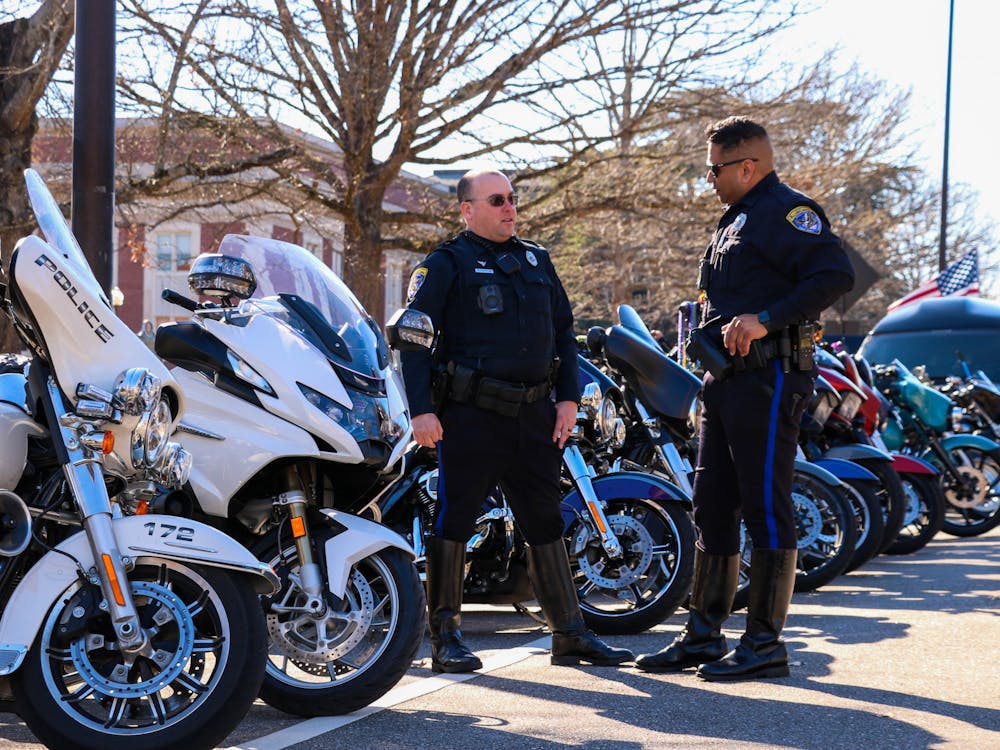 Two officers with the Auburn Police Department chat in front of a row of motorcycles set to lead Auburn's Mardi Gras parade held on Feb. 18, 2023.