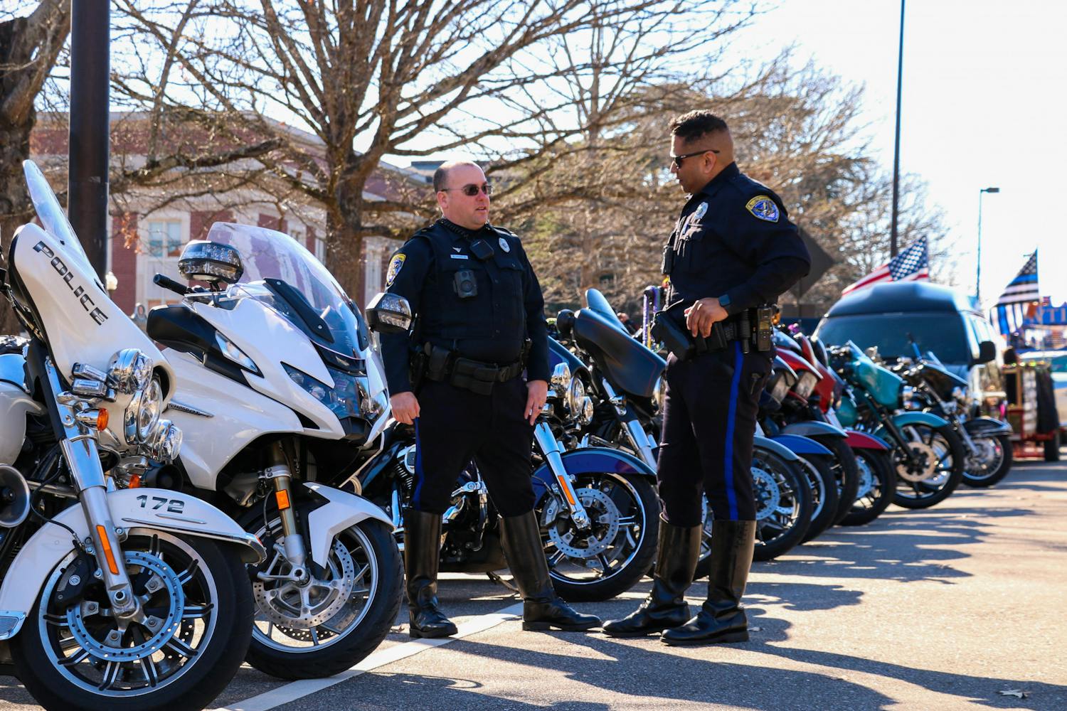 Two officers with the Auburn Police Department chat in front of a row of motorcycles set to lead Auburn's Mardi Gras parade held on Feb. 18, 2023.