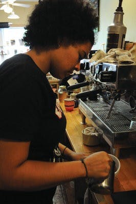 Alyssa Carodine, junior in anthropology and barista at Gnu's Room, makes a drink with latte art. (Christen Harned / ASSOCIATE PHOTO)