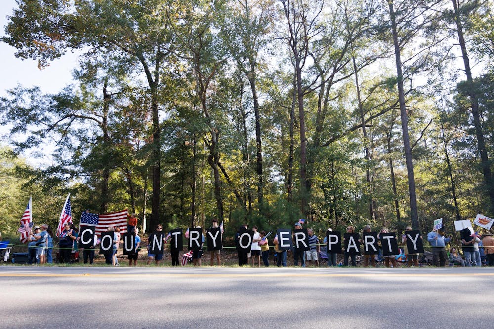 <p>Protestors from the No Kings protest hold signs with letters lit up to spell "Country Over Party" at one end of the long line of attendees on Saturday, Oct. 18, 2025.</p>
