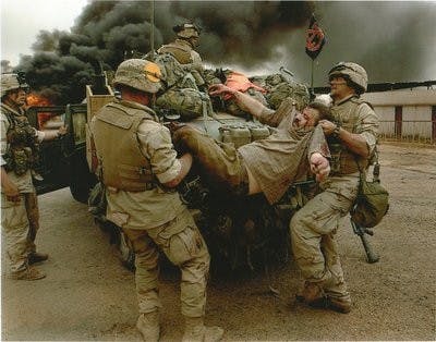 Ian Hogg (far left), a sergeant in the U.S. Marine Corps, oversees members of his unit lifting an injured man into Hogg's humvee, on which he displayed an Auburn flag. Hogg served in Iraq from January to June of 2003. He is now fighting Lou Gehrig's disease. (Contributed by MISTY Hogg)