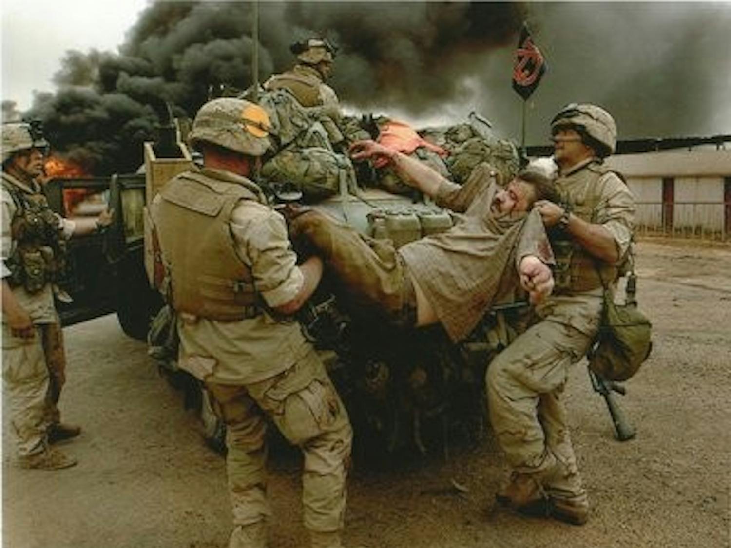 Ian Hogg (far left), a sergeant in the U.S. Marine Corps, oversees members of his unit lifting an injured man into Hogg's humvee, on which he displayed an Auburn flag. Hogg served in Iraq from January to June of 2003. He is now fighting Lou Gehrig's disease. (Contributed by MISTY Hogg)