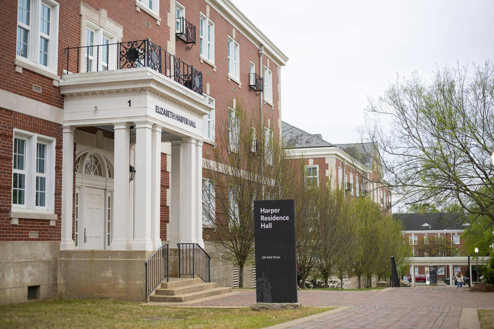 A red brick building features a white portico with columns, leading to a door labeled "Elizabeth Harper Hall," alongside a sign for "Harper Residence Hall."