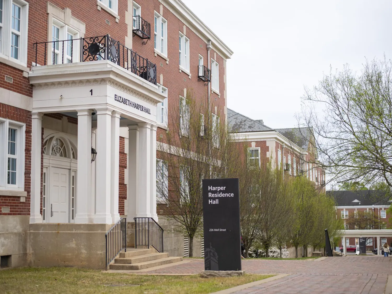 A red brick building features a white portico with columns, leading to a door labeled "Elizabeth Harper Hall," alongside a sign for "Harper Residence Hall."