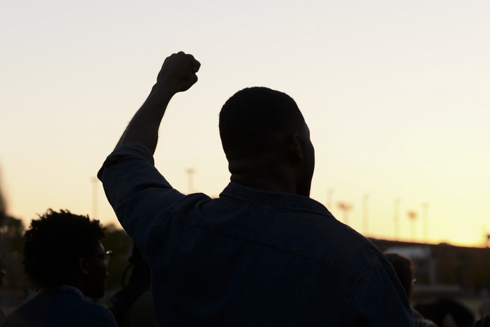 <p>A student holds his fist up during a chant during a sit-in protest at the Student Center Greenspace.</p>
