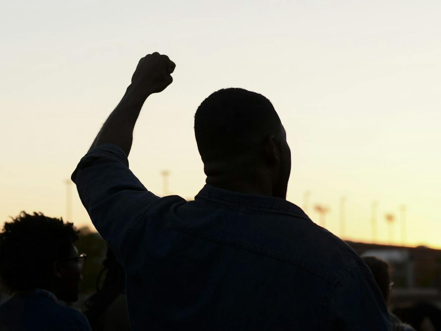 A student holds his fist up during a chant during a sit-in protest at the Student Center Greenspace.