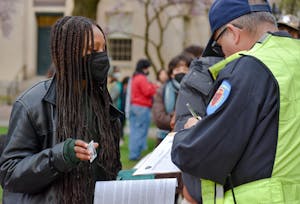 A DPS officer is writing down the ID number of a student protestor.