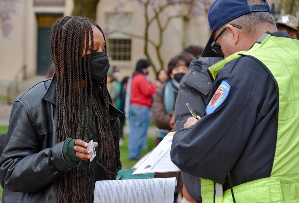 A DPS officer is writing down the ID number of a student protestor.